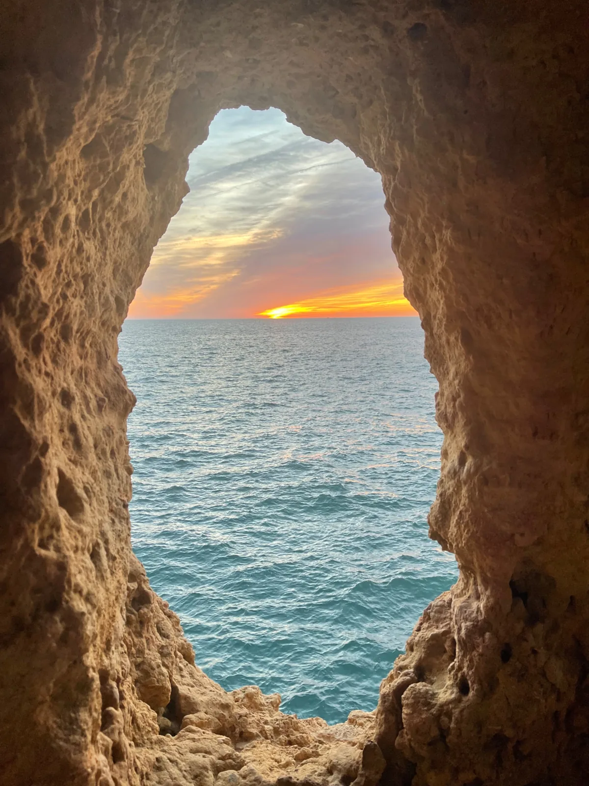 A natural window in the rock at Algar Seco framing the sea at sunset