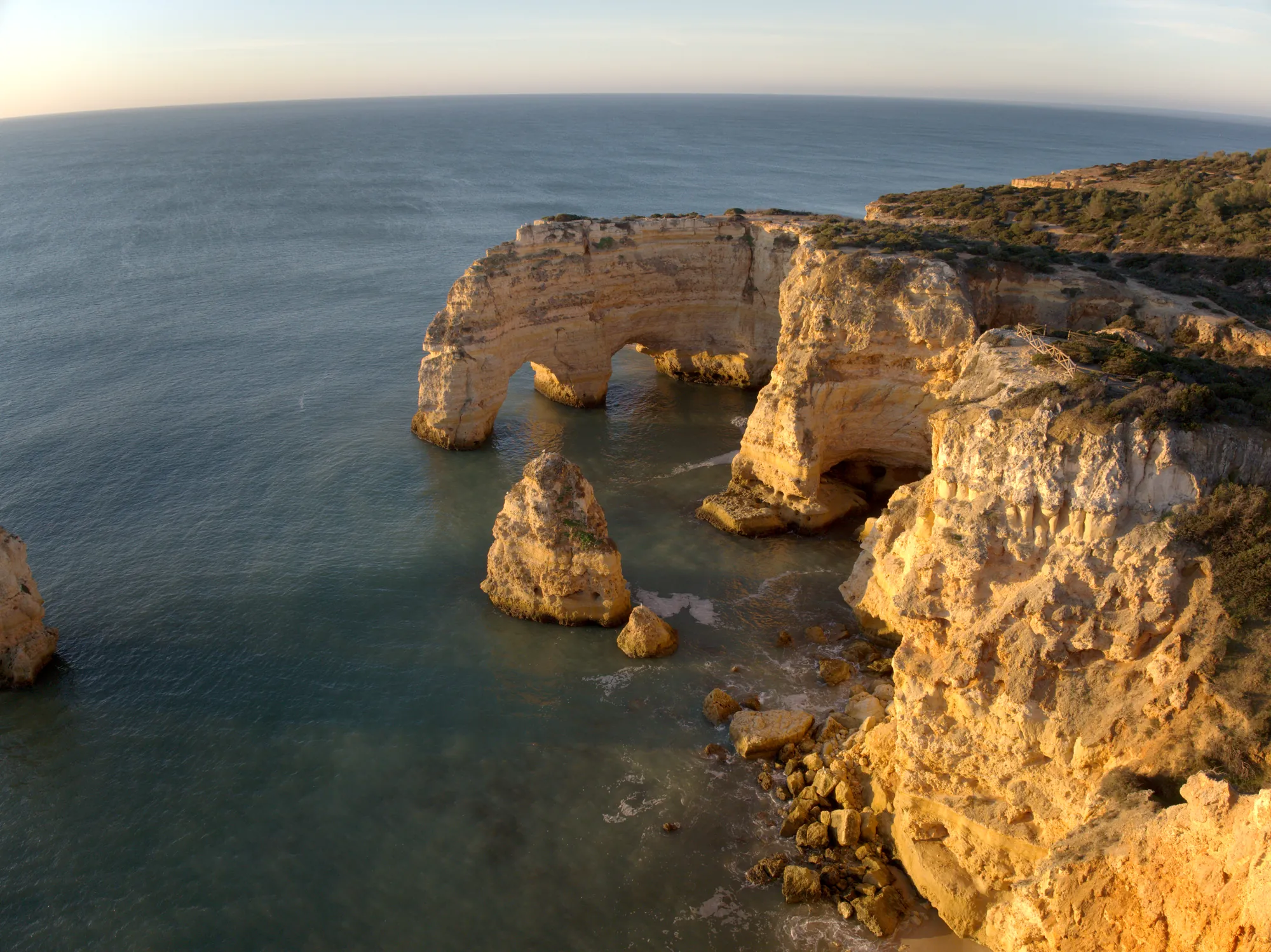 Sea stacks and the double arch at Praia da Marinha seen from the air at sunrise