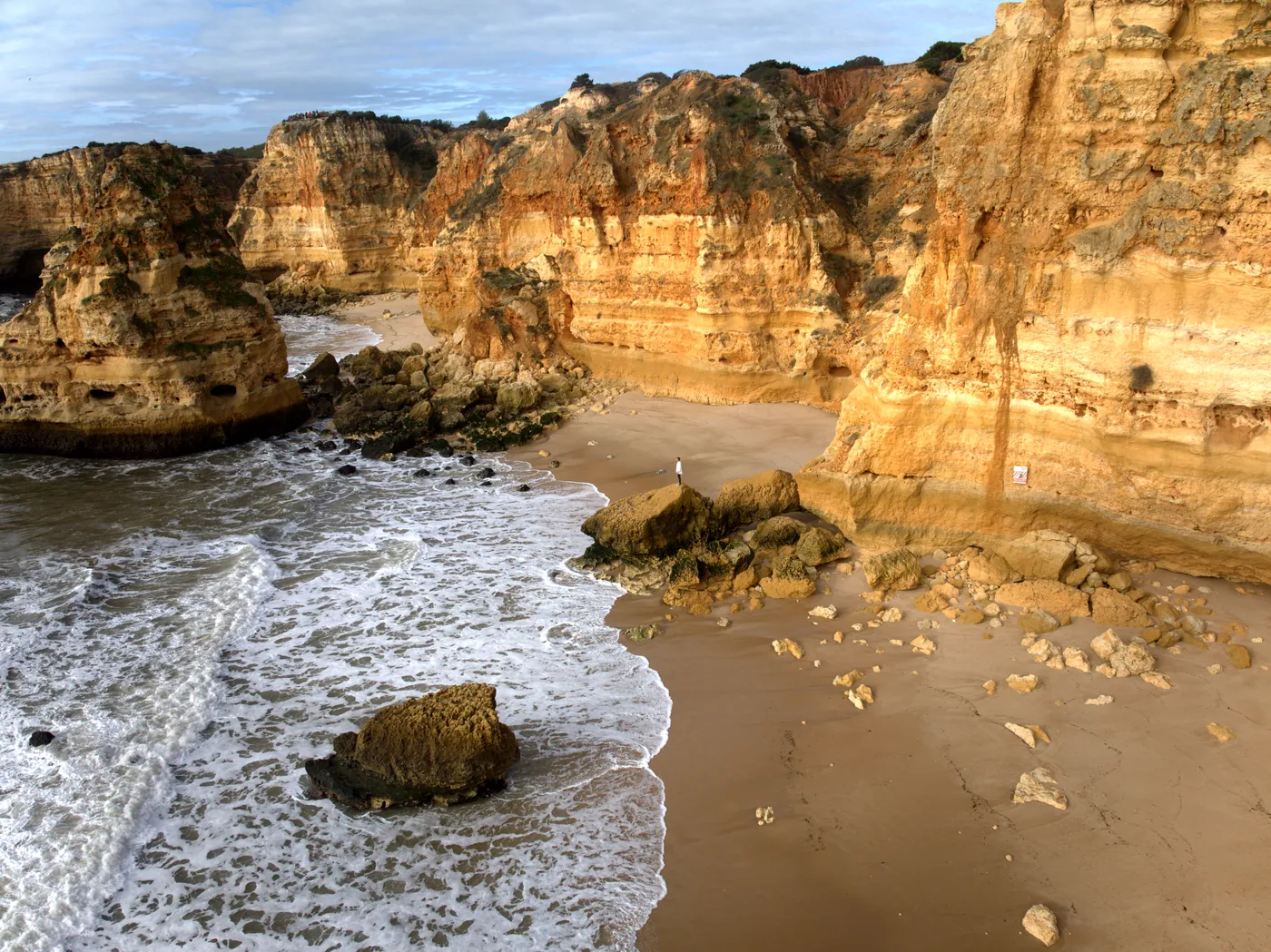 The sand at Praia da Marinha below golden cliffs, with rocks at the water's edge