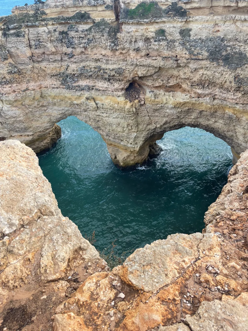 A heart-shaped opening in the cliff top above the sea near Praia da Marinha